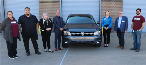 A group of adults stands around a car